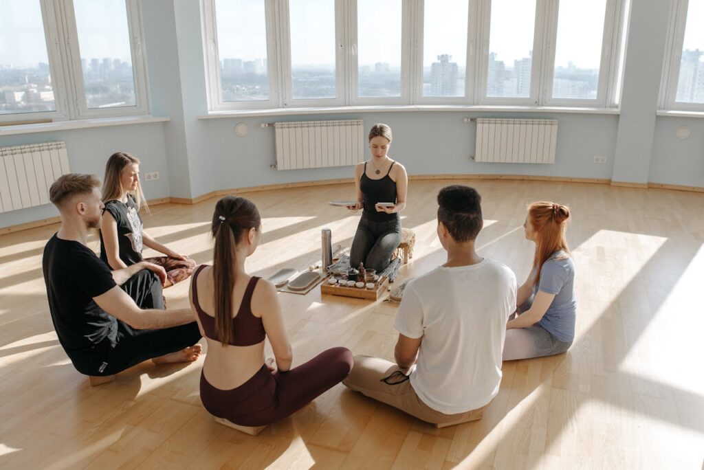 Diverse group meditating in a sunlit room, promoting peace and relaxation.